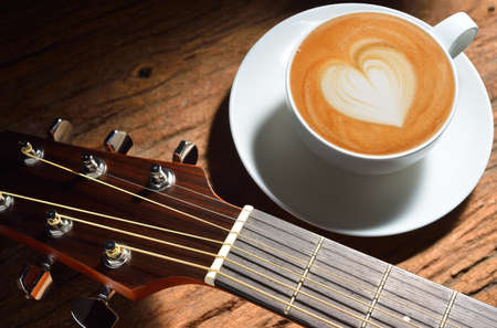 Latte art and guitar on wooden table