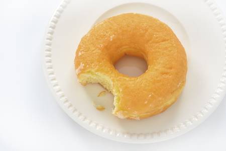 bitten donut on a dish, isolated on white の写真素材
