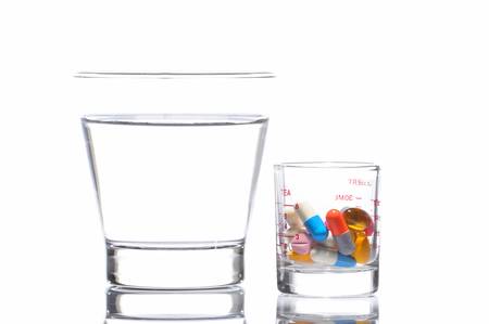 Pills and a glass of water on white