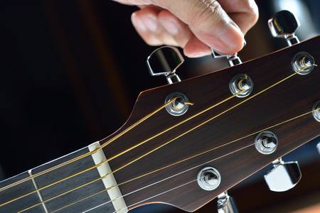 	Hand tuning a guitar from headstock