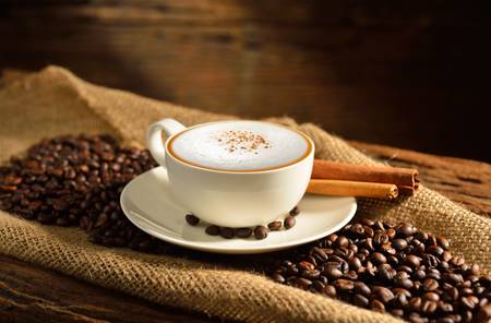 A cup of cappuccino and coffee beans A cup of cappuccino and coffee beans