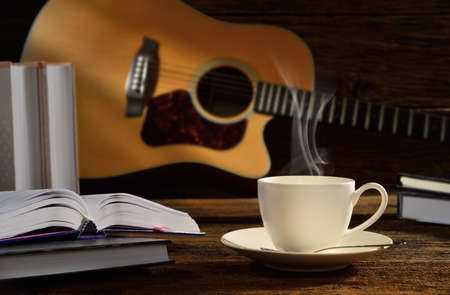 Cup of coffee with books and guitar on wooden table の写真素材