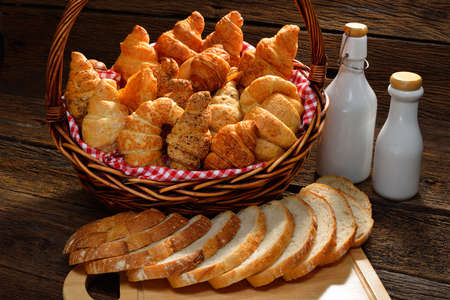 Variety of bread in wicker basket on old wooden background の写真素材