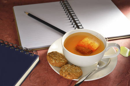 Cup of tea with tea bag and cookies on tableの写真素材
