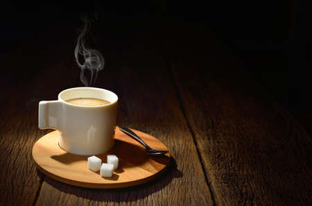 Cup of coffee with smoke and sugar cube on old wooden backgroundの写真素材