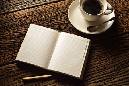 Blank notepad and coffee cup on old wooden table