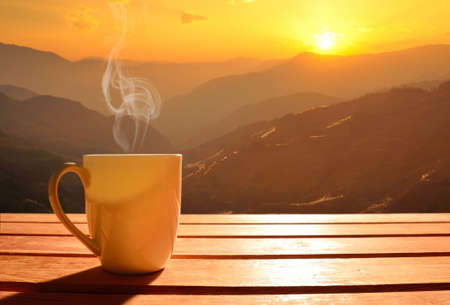 Morning cup of coffee with mountain background at sunriseの写真素材