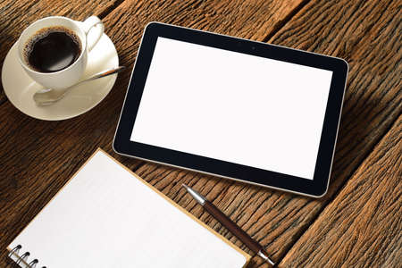 Tablet computer with notepad and coffee cup on old wooden backgroundの写真素材