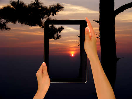 Woman hands holding tablet pc taking photo in natureの写真素材