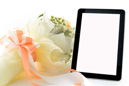 Tablet computer and bouquet of flowers isolated on whiteの写真素材