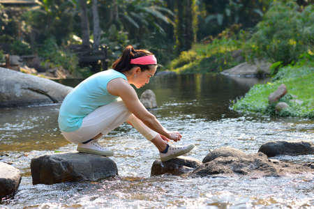 Middle aged woman runner tying shoelaces outdoorの写真素材