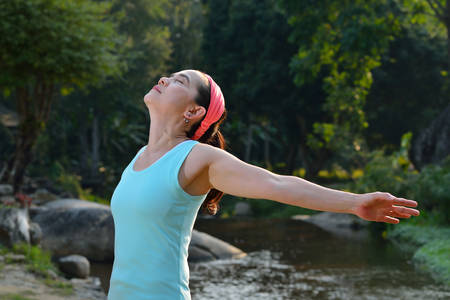 Woman stretching her arms to enjoy the fresh air in the park
