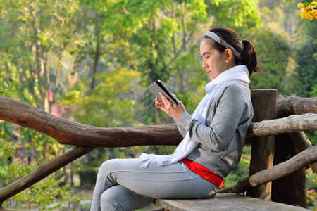 Middle aged woman using tablet computer in the parkの写真素材