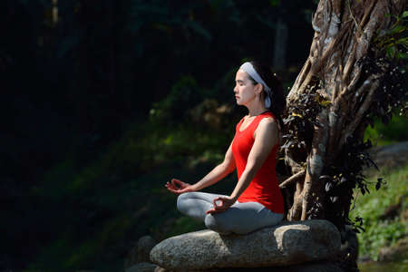 Middle aged woman practicing yoga meditation outdoorの写真素材