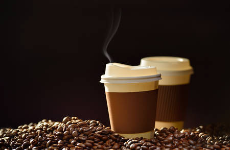 Paper cup of coffee and coffee beans on wooden tableの写真素材