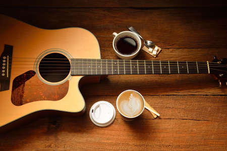 Cups of coffee and guitar on wooden tableの写真素材