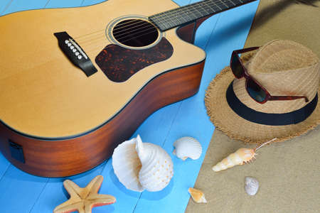 Acoustic guitar with starfish and seashells on the beachの写真素材