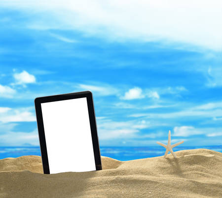 Tablet computer with starfish on the beach with blue sea and skyの写真素材