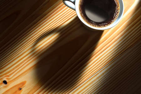 Top view of a cup of coffee in the morning light on wooden backgroundの写真素材