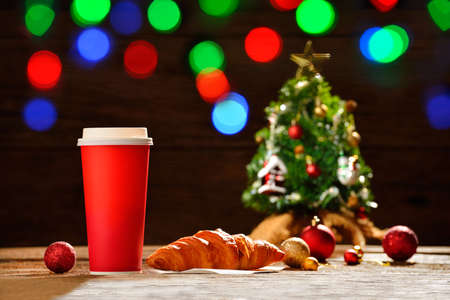 Paper coffee cup with Christmas decorations on bokeh background of Christmas lightsの写真素材