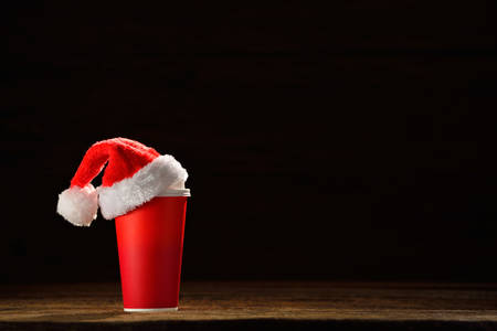 Paper coffee cup with santa's hat on top on black backgroundの写真素材