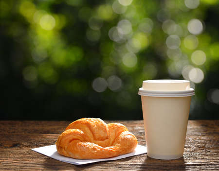 Paper cup of coffee and croissant in the garden,copy space backgroundの写真素材