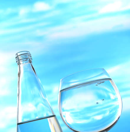 Fresh and clean drinking water in bottle and glass on sky backgroundの写真素材
