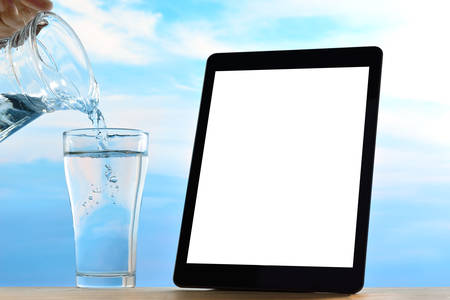 Tablet computer with fresh and clean drinking water on sky backgroundの写真素材