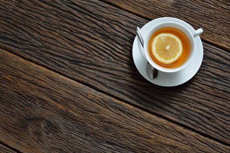 Top view of cup of tea with lemon on wooden tableの写真素材