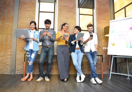 Group of businesspersons with age variety holding electronic devices and gadgets in the officeの写真素材