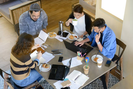 Group of business people having different age in creative business discussing work in coffee shop