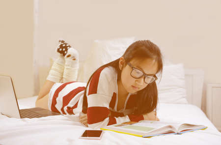 Young teenage girl reading story book on the bedの写真素材