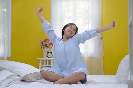 Young teenage girl stretching in bed after wake upの写真素材
