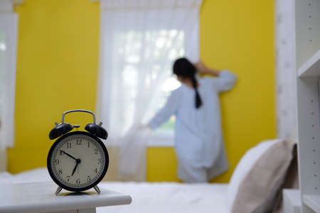 Woman in the morning looking at the sunrise standing near the window in bed room