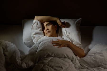 Woman with insomnia lying in bed with open eyesの写真素材