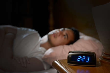 Depressed man suffering from insomnia lying in bedの写真素材