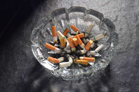 Many cigarette butts and ashes piled in an ashtrayの写真素材