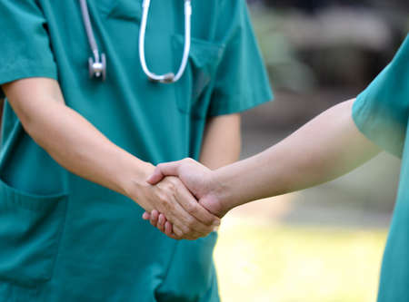 Doctors in a medical team handshake together outdoor on the green park background (volunteer)の写真素材