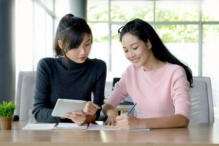 Two female colleagues working together in office