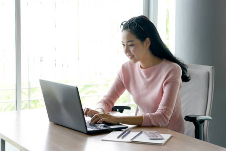 Portrait of businesswoman smiling at a laptop computer in the officeの写真素材