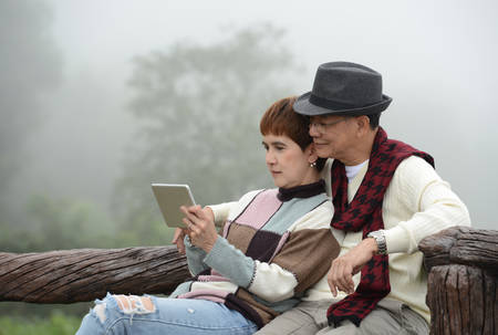 Portrait of happy senior couple using digital tablet outdoorsの写真素材