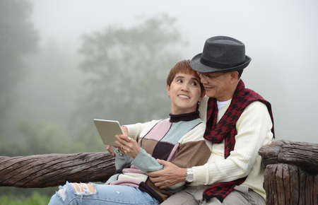 Portrait of happy senior couple using digital tablet outdoorsの写真素材