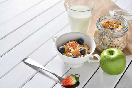 Healthy food, healthy muesli breakfast with milk and fruits on white wooden tableの写真素材