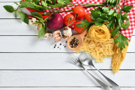 Pasta spaghetti, farfalle, linguine with vegetables and spices on white wooden tableの写真素材