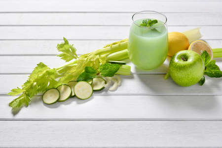 Glass of fruit and vegetable juice on white wooden table