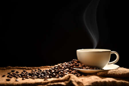 Cup of coffee with smoke and coffee beans on wooden backgroundの写真素材