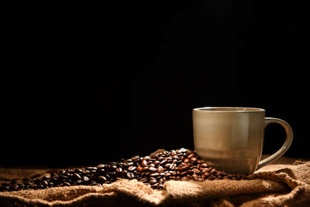 Coffee cup and coffee beans on black background
