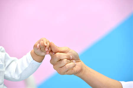 Baby's hand holding doctor's finger in hospitalの写真素材