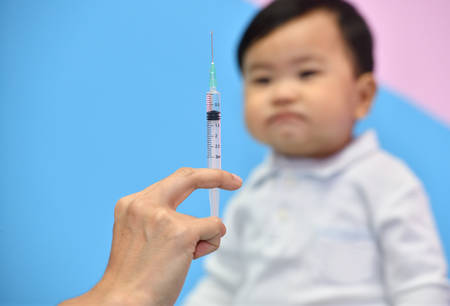 Doctor holding syringe with vaccine for Asian baby in hospitalの写真素材