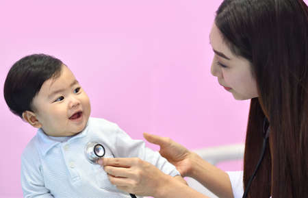 Asian pediatrician examining a baby with a stethoscope in a hospitalの写真素材